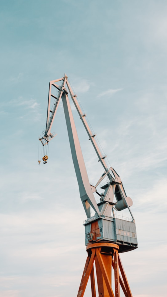 A large industrial crane, a marvel of civil engineering recruitment, stands tall against a cloudy sky.